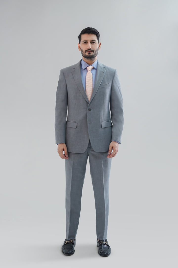 Man wearing a gray suit with a light blue shirt and pink tie on a white background